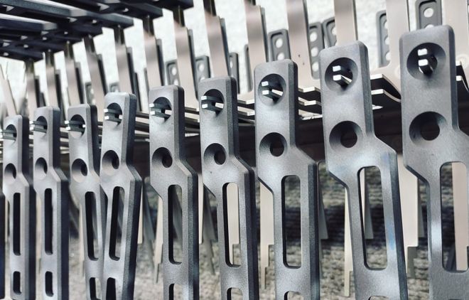 Clear anodized aluminum parts hanging on racks after a hardcoat application.